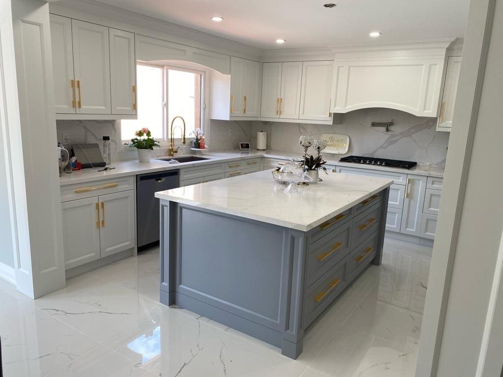 Renovated kitchen with a grey painted island, quartz counters and a marble pattern backsplash